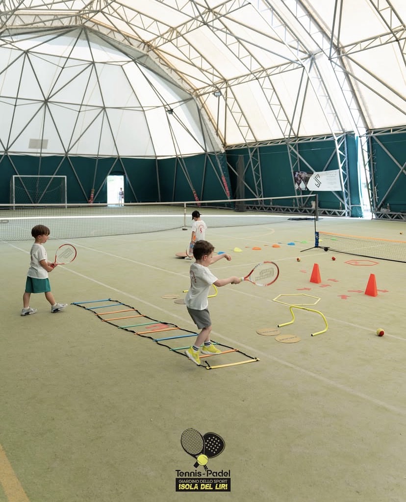 Bambini durante la scuola tennis sul campo coperto con esercizi di coordinazione