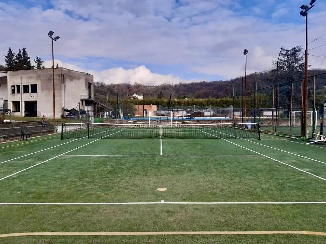 Campo da tennis in sintetico verde con illuminazione