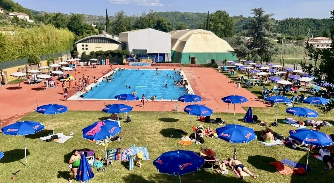 La piscina 25 x 12,5 metri con ombrelloni e prato durante l'estate